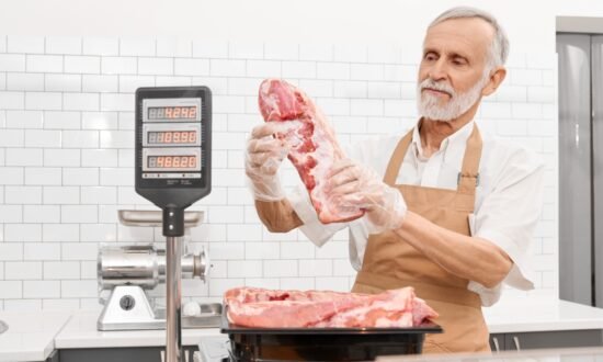 Butcher using a stainless steel NTEP certified price computing scale at a meat counter in a butcher shop