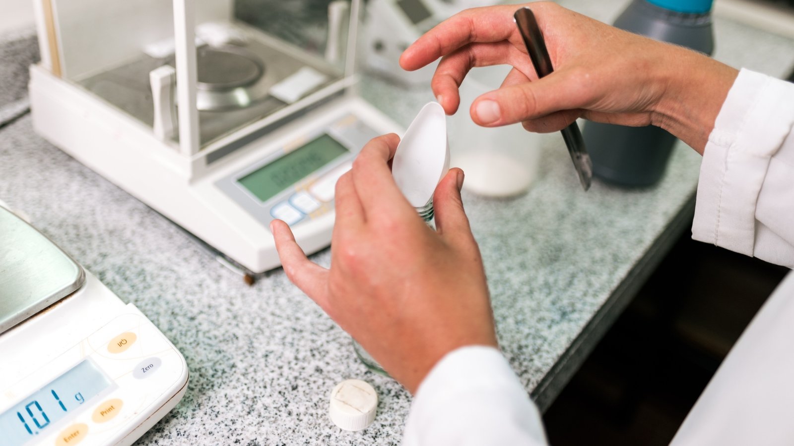 Side by side comparison of an analytical balance with draft shield and a precision top loading balance in a laboratory