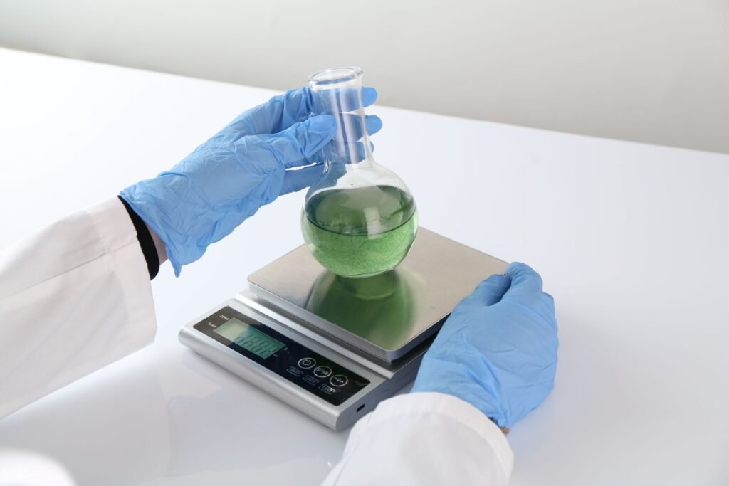 Laboratory technician using a precision top-loading balance for routine buffer preparation and solution making in a general chemistry laboratory