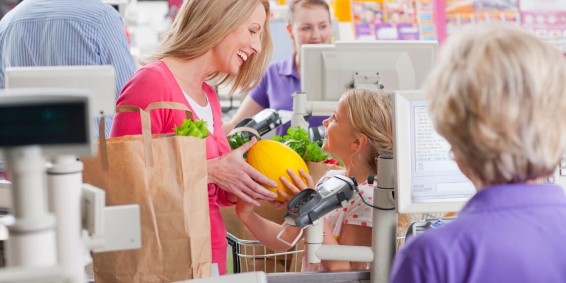 Grocery store checkout lane with an integrated POS scale platform at the register weighing fresh produce during a customer transaction