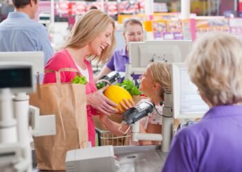 Grocery store checkout lane with an integrated POS scale platform at the register weighing fresh produce during a customer transaction