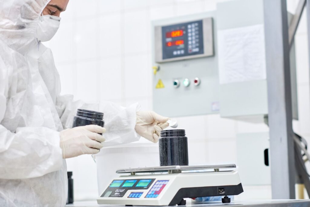 Pharmaceutical quality control technician using a precision balance to weigh active pharmaceutical ingredients in a regulated laboratory