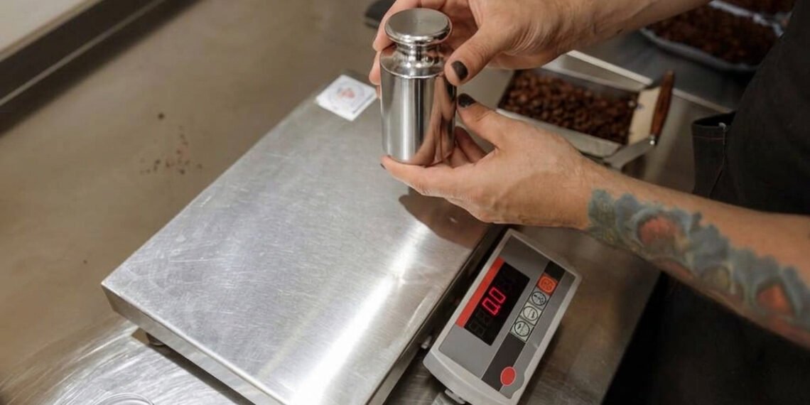 Scale calibration technician placing NIST-traceable certified test weights on an industrial floor scale in a manufacturing facility