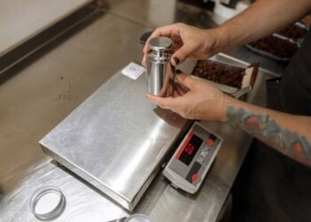 Scale calibration technician placing NIST-traceable certified test weights on an industrial floor scale in a manufacturing facility