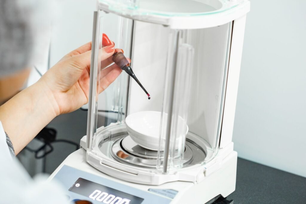 Analytical balance with enclosed draft shield being used for pharmaceutical API weighing in a GMP quality control laboratory