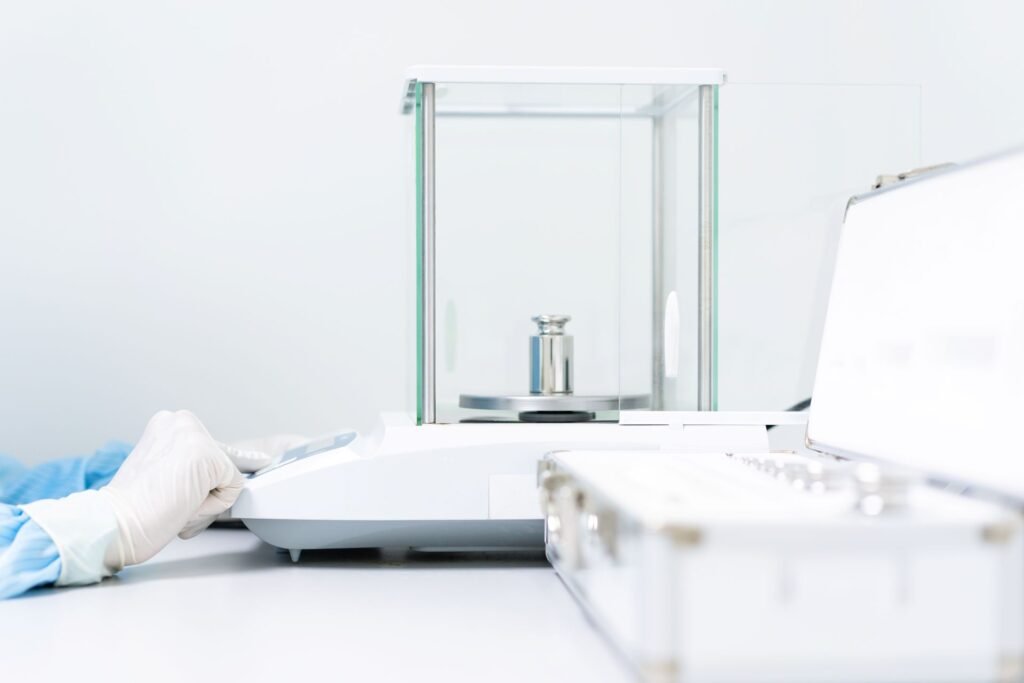 Analytical balance performing automatic internal calibration routine on a laboratory bench in a GMP quality control environment