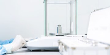 Laboratory analyst performing a ten-replicate precision verification test on an analytical balance using a certified reference weight