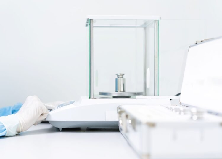 Laboratory analyst performing a ten-replicate precision verification test on an analytical balance using a certified reference weight