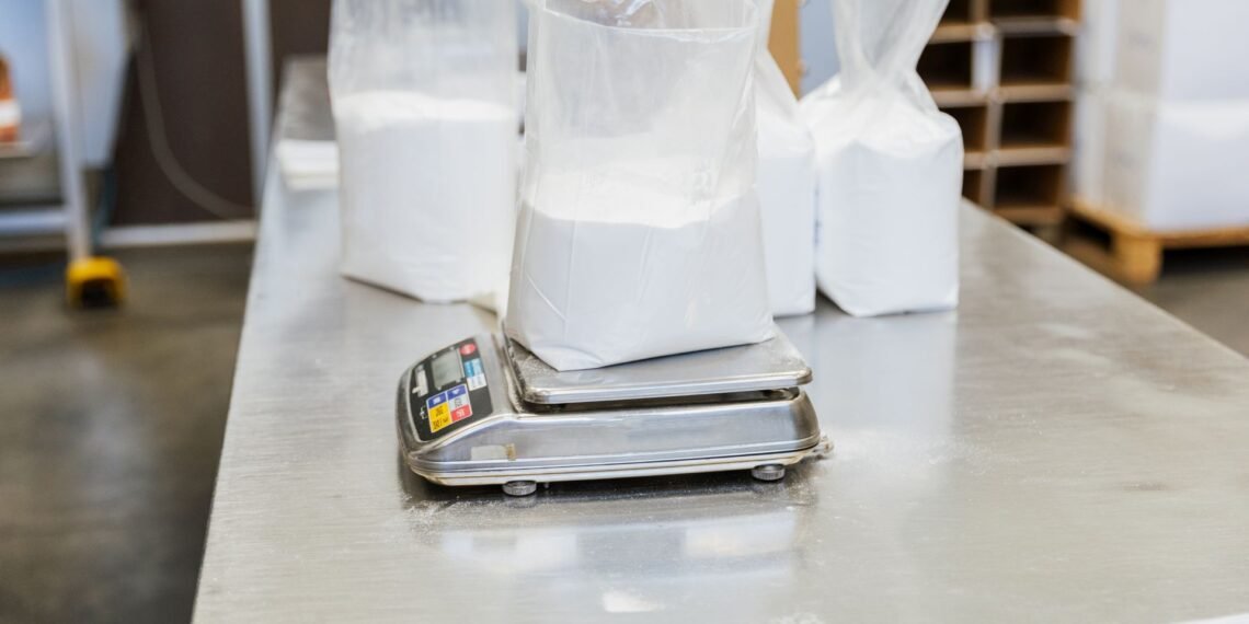 Industrial bench scale on a manufacturing packing workstation with an operator verifying package weight at standing height