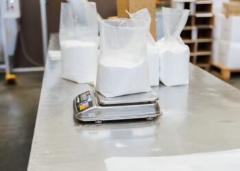 Industrial bench scale on a manufacturing packing workstation with an operator verifying package weight at standing height