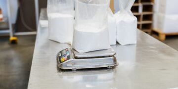 Industrial bench scale on a manufacturing packing workstation with an operator verifying package weight at standing height