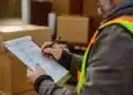 Warehouse shipping manager reviewing a completed Bill of Lading document at a loading dock before LTL carrier pickup