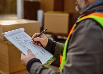 Warehouse shipping manager reviewing a completed Bill of Lading document at a loading dock before LTL carrier pickup