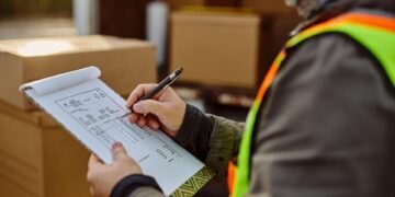 Warehouse shipping manager reviewing a completed Bill of Lading document at a loading dock before LTL carrier pickup