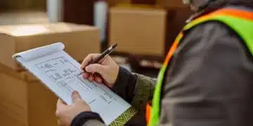 Warehouse shipping manager reviewing a completed Bill of Lading document at a loading dock before LTL carrier pickup