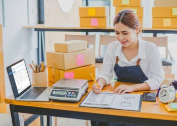 Business owner at a packing station using a USB-connected shipping scale to weigh packages before generating shipping labels