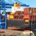Loaded shipping containers being lifted by crane at a port terminal before vessel loading under SOLAS VGM requirements