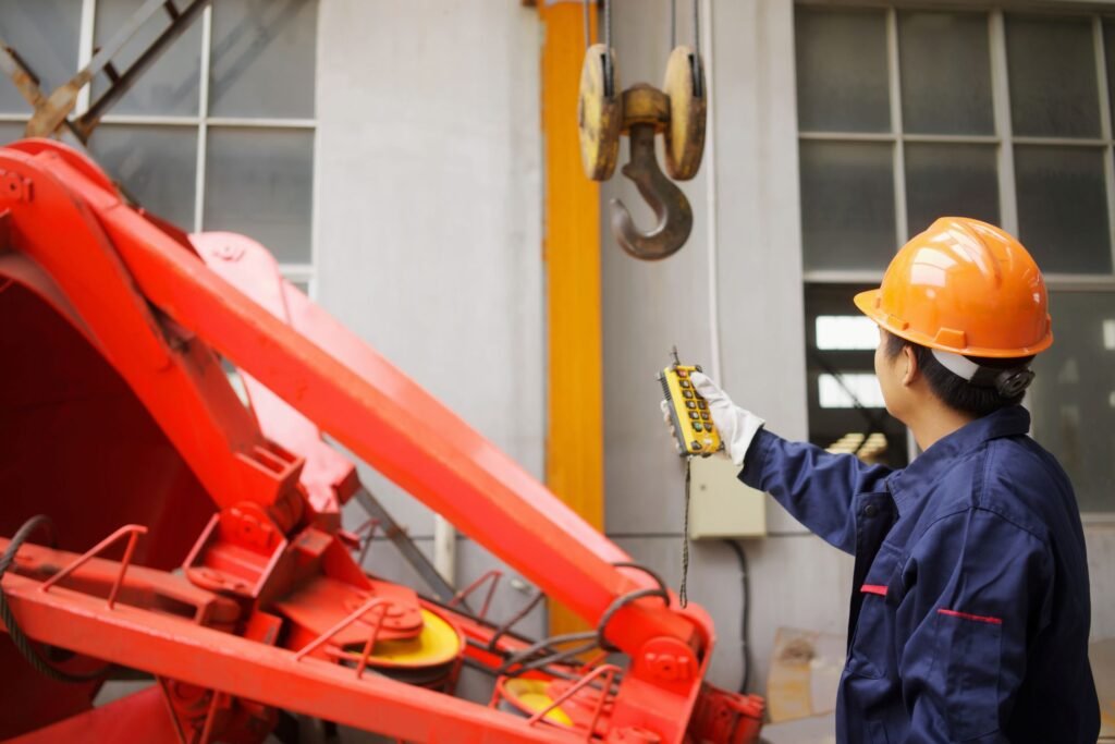 Crane operator reading weight from a wireless remote display at floor level during an overhead lifting operation in a warehouse