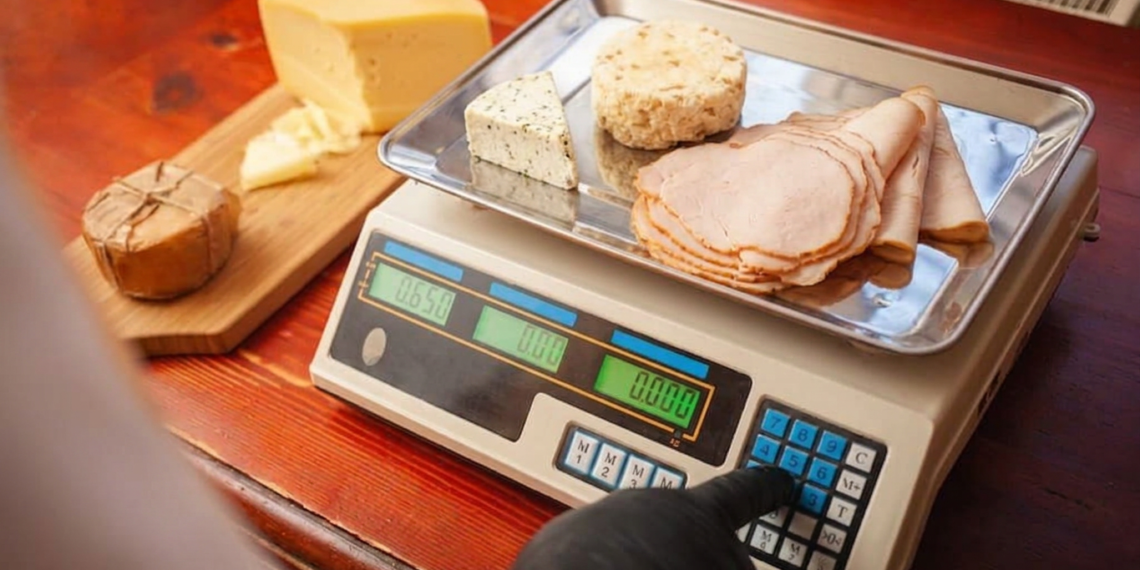 NTEP-certified deli counter scale with dual display showing weight and price while operator slices turkey for customer