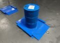 55-gallon drum being rolled onto a low-profile drum scale at an industrial chemical facility for incoming material weight verification