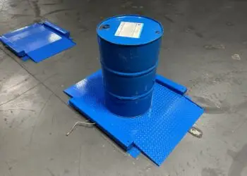 55-gallon drum being rolled onto a low-profile drum scale at an industrial chemical facility for incoming material weight verification