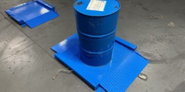 55-gallon drum being rolled onto a low-profile drum scale at an industrial chemical facility for incoming material weight verification