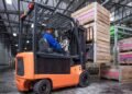 Forklift with integrated load cell scale system weighing a loaded pallet in a large warehouse distribution center