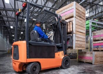 Forklift with integrated load cell scale system weighing a loaded pallet in a large warehouse distribution center