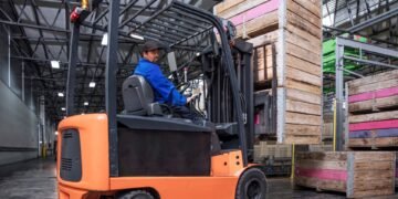 Forklift with integrated load cell scale system weighing a loaded pallet in a large warehouse distribution center