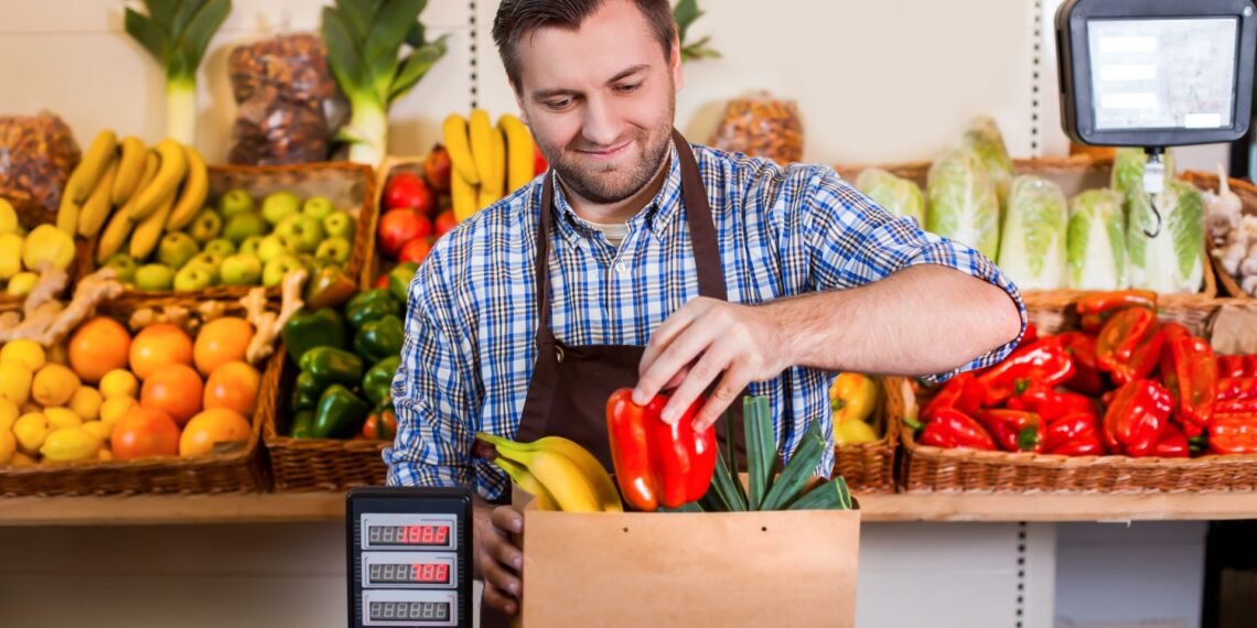 Grocery store produce department with digital price computing scale showing weight and price per pound for fresh fruits and vegetables