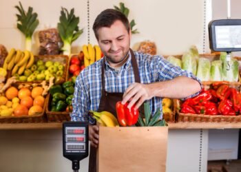 Grocery store produce department with digital price computing scale showing weight and price per pound for fresh fruits and vegetables