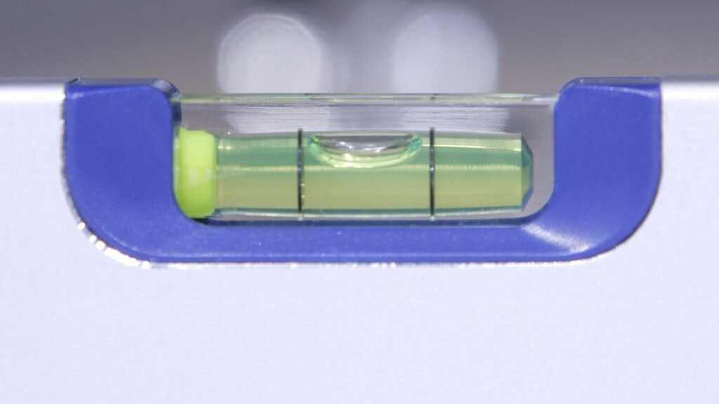 Laboratory technician checking the bubble level indicator on an analytical balance and adjusting the leveling feet before a weighing session