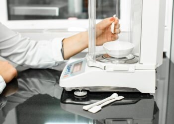Laboratory scientist using an analytical balance with draft shield in a pharmaceutical research and quality control laboratory