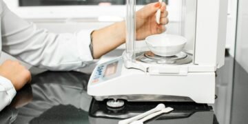 Laboratory scientist using an analytical balance with draft shield in a pharmaceutical research and quality control laboratory