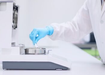 Laboratory technician placing a sample in a halogen moisture analyzer in a pharmaceutical quality control laboratory