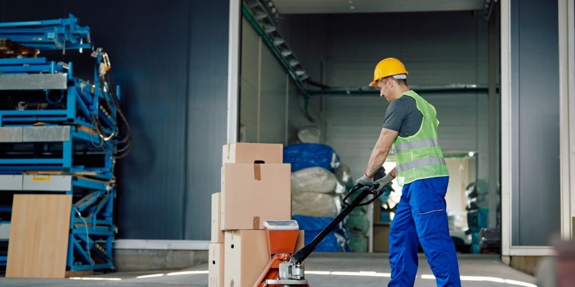 Warehouse operator using a digital pallet jack scale to weigh a loaded pallet during transport in a distribution center