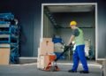 Warehouse operator using a digital pallet jack scale to weigh a loaded pallet during transport in a distribution center