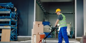 Warehouse operator using a digital pallet jack scale to weigh a loaded pallet during transport in a distribution center