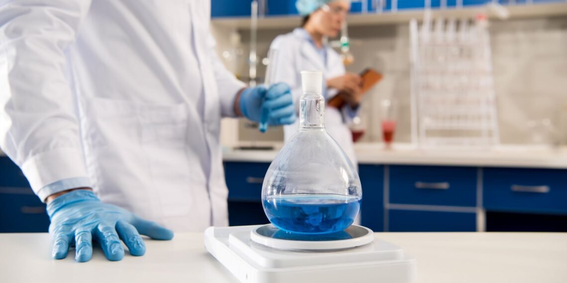 Pharmaceutical QC analyst weighing an active pharmaceutical ingredient on an analytical balance in a GMP compliant laboratory