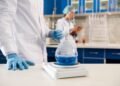 Pharmaceutical QC analyst weighing an active pharmaceutical ingredient on an analytical balance in a GMP compliant laboratory