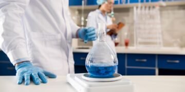 Pharmaceutical QC analyst weighing an active pharmaceutical ingredient on an analytical balance in a GMP compliant laboratory