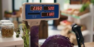 Retail operator setting up a price computing scale on a deli counter checking the bubble level indicator before programming PLU prices