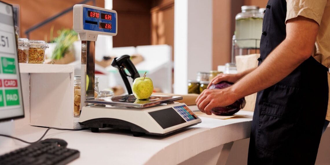 Business owner reviewing retail scale options at a deli counter showing price computing scale with dual customer display