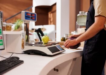 Business owner reviewing retail scale options at a deli counter showing price computing scale with dual customer display