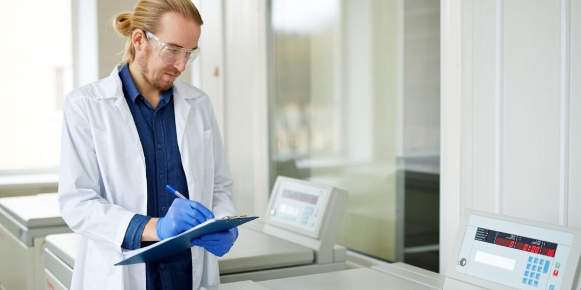 Laboratory scientist evaluating an analytical balance specification sheet next to an instrument in a research laboratory