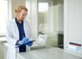 Laboratory scientist evaluating an analytical balance specification sheet next to an instrument in a research laboratory