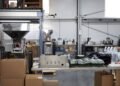 Warehouse operator weighing a fully sealed shipping package on a digital scale connected to shipping software at a packing station