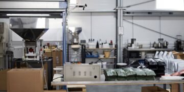 Warehouse operator weighing a fully sealed shipping package on a digital scale connected to shipping software at a packing station
