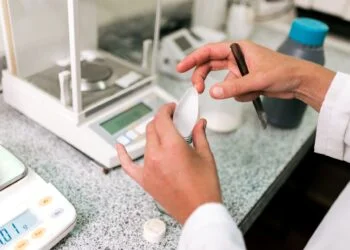 Top loading balance with open pan next to an analytical balance with enclosed draft shield on a laboratory bench for side by side comparison