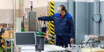 Calibration technician placing a certified NIST-traceable test weight on a warehouse floor scale during professional calibration